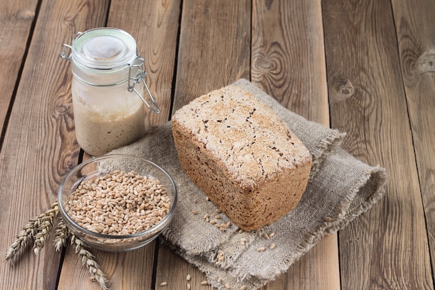 Photo a loaf of bread made from spelt flour on a flour leaven on a natural wooden table.