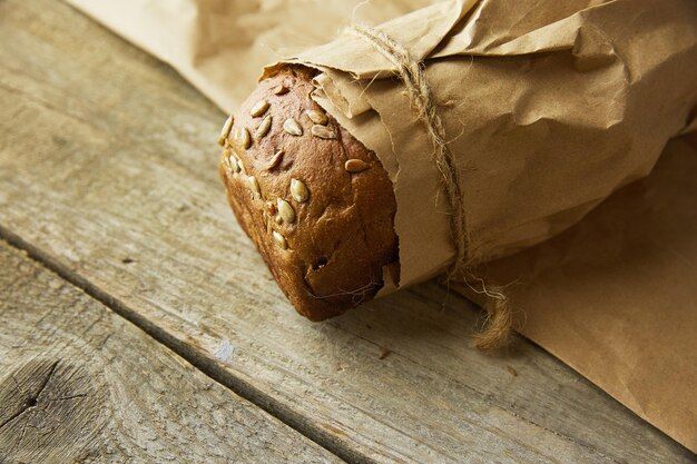 A loaf of Bread packed in paper on wooden table