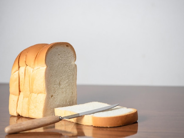 Loaf bread slice with knife on table copy space