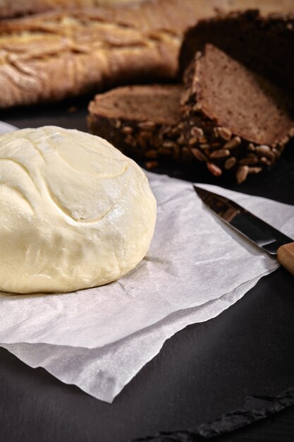 Loaf of bread with butter and knife dark table, side view