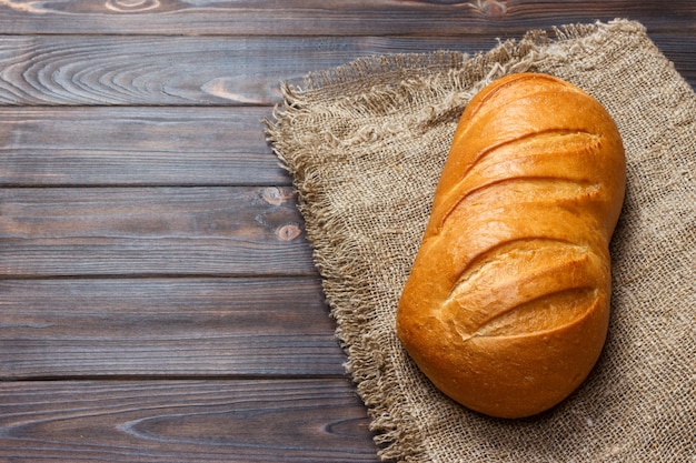 Loaf of bread on wooden background, food closeup