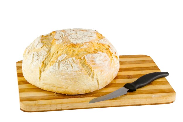 Loaf of bread on a wooden board and knife