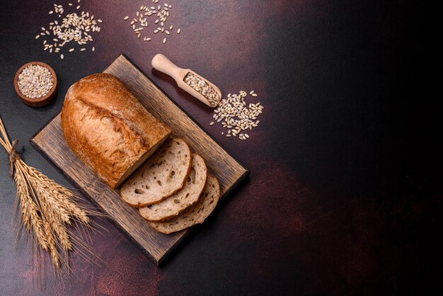 A loaf of brown bread with grains of cereals on a wooden cutting board