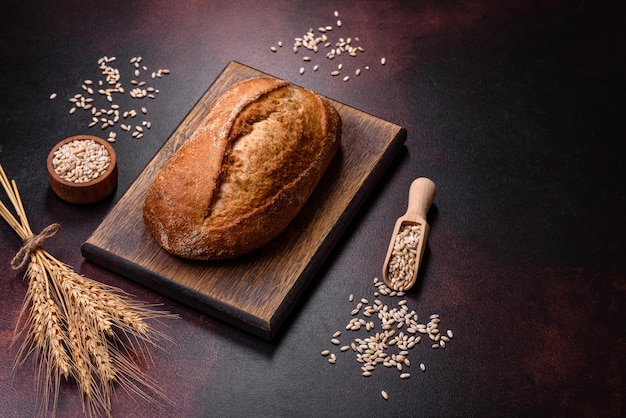 A loaf of brown bread with grains of cereals on a wooden cutting board