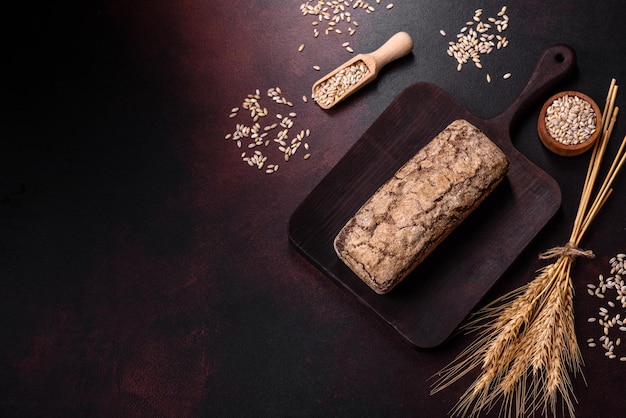 A loaf of brown bread with grains of cereals on a wooden cutting board