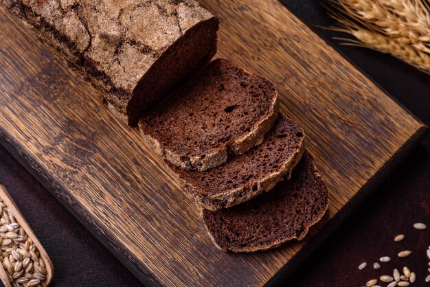 A loaf of brown bread with grains of cereals on a wooden cutting board