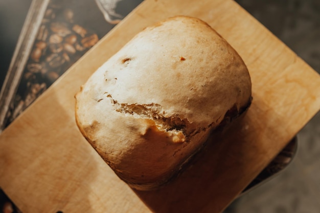 A loaf of fresh fluffy homemade bread baked in a bread machine on a wooden board