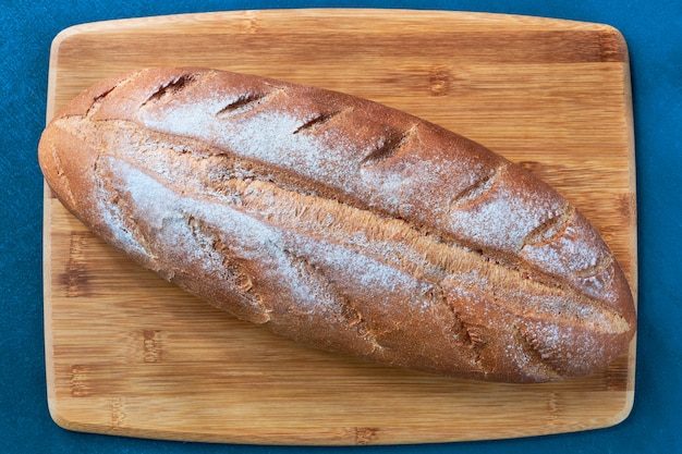 나무 판자에 갓 구운 흰 빵 한 덩어리를 닫습니다.