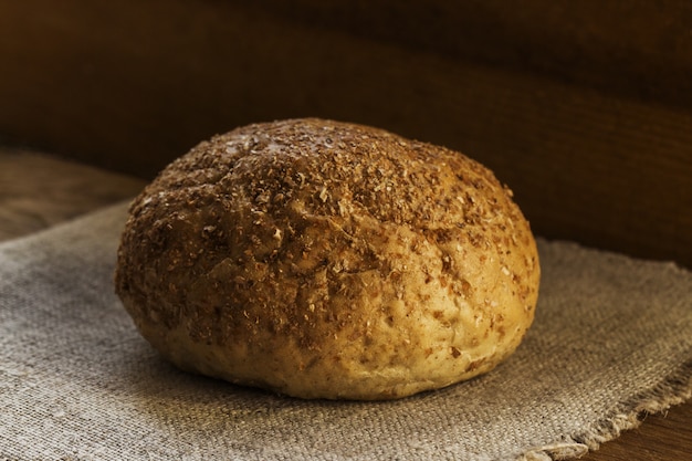 A loaf of rye bread lies on a natural blue textile napkin