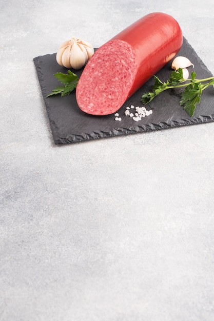 A loaf of salami sausage on a black cutting on light background