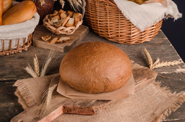 Loaf of traditional round rye bread on wooden background and burlap