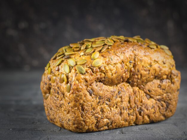 A loaf of whole-grain bread, on black rustic table