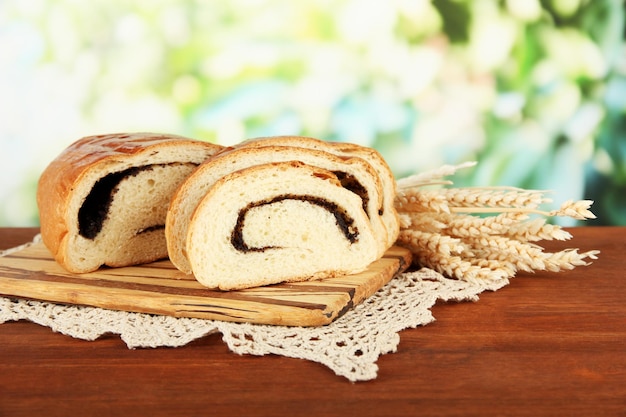 Loaf with poppy seed on cutting board on bright background