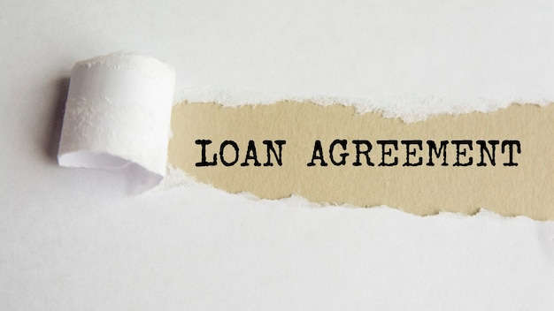 Loan agreement. words. text on gray paper on torn paper background.