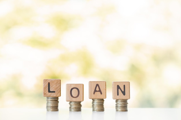 Loan word written on wood cubes stacks of coins nature green background