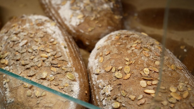 Loaves of rye farm bread lie on the wooden bakery shelf Closeup shot Shopping at the grocery store Selling food concept