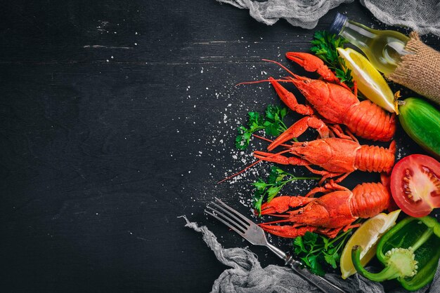 Lobster and fresh vegetables. Seafood. On a wooden background. Top view. Free space for your text.