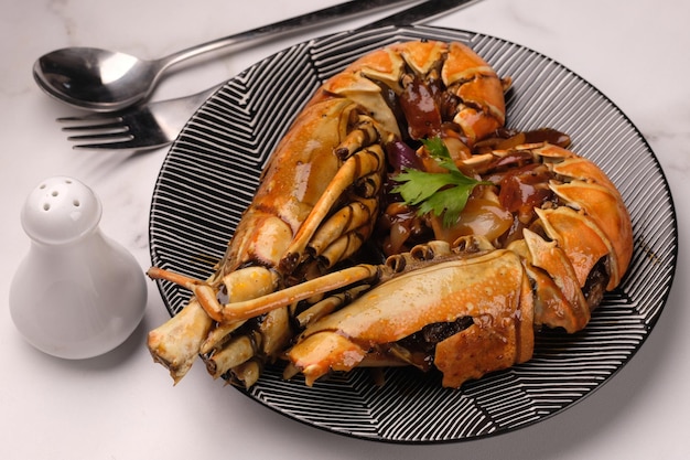 Lobster saus lada hitam or Lobster in black pepper sauce. Served on a ceramic plate.