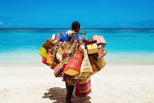 Местный продавец-мужчина продает пляжные аксессуары ручной работы на берегу моря