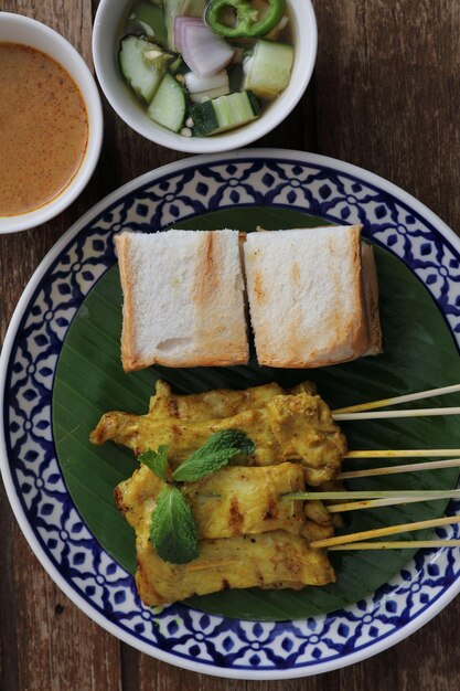 Local thai food pork satay with oeanut dipping sauce isolated in wood background