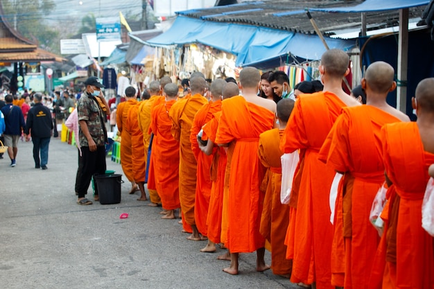 지역 주민들은 아침에 부처님들에게 음식과 쌀을 제공합니다. 사제 몽크는 아름다운 전통 문화로 사원에서 도시로 곰 발을 들고 걷는다.