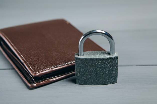 Lock on a black wallet. concept of saving money on a gray\
wooden table