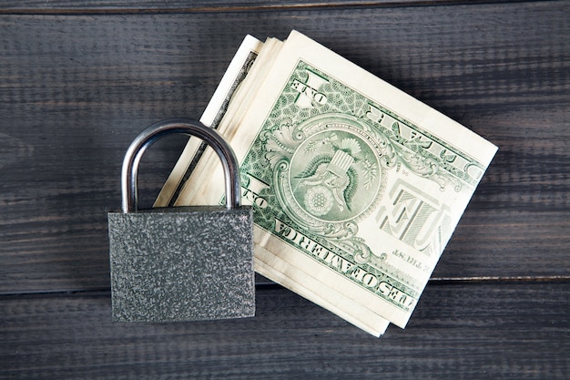 Lock on dollar bills on gray wooden table