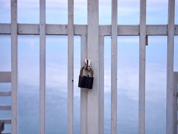 Photo lock on a metal white handrail fence against the sea