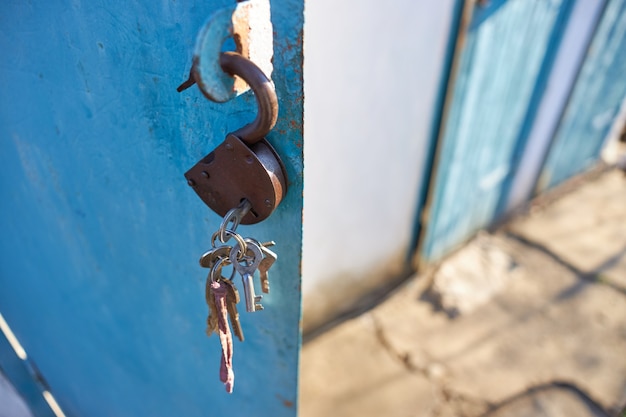 A lock with a bunch of keys hanging in an open metal door