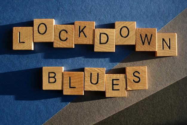 Foto parole di lockdown blues in lettere di alfabeto in legno isolate su uno sfondo blu-grigio e nero