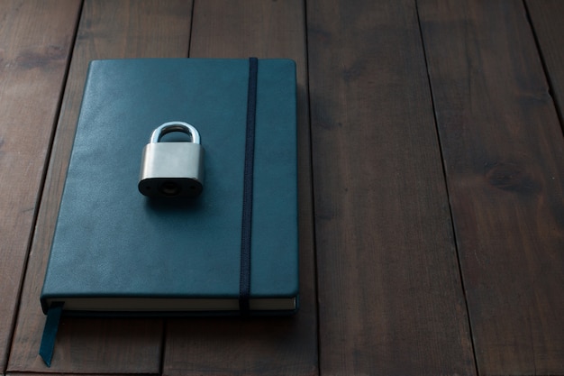 Locked and key on Blue notebook on wooden background