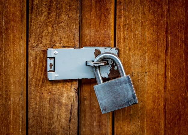 Locked padlock with chain at wooden door background