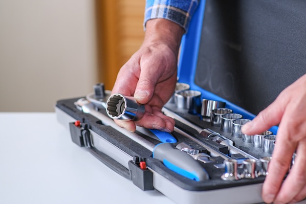 Photo locksmith in a checked shirt holds a key attachment in his hand.