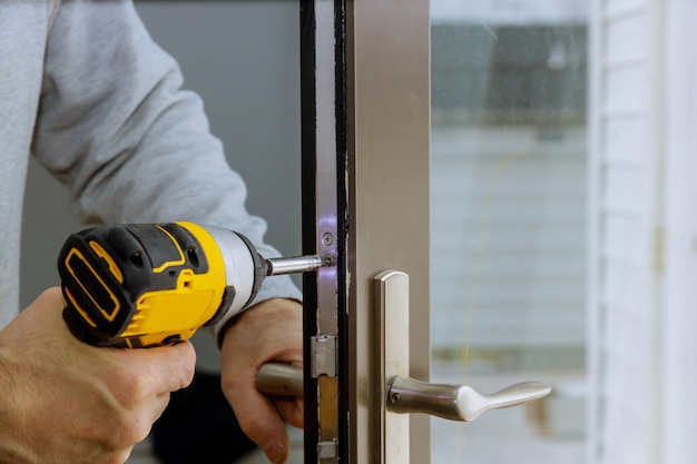 Locksmith hand holds the screwdriver in installing door lock