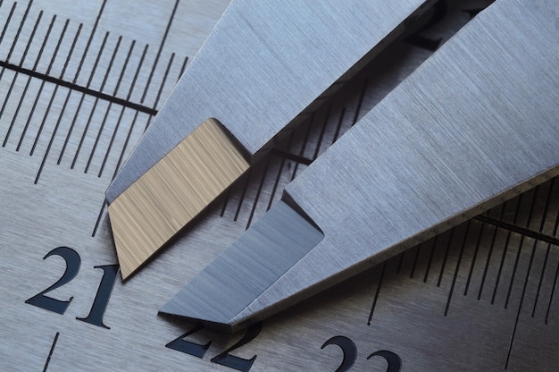 Locksmith measuring tool lies on the background of metal rulers closeup