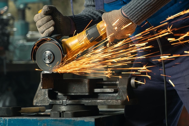 특수 옷과 고글의 자물쇠 제조공은 앵글 그라인더 스파가 있는 생산 금속 가공에서 일합니다.