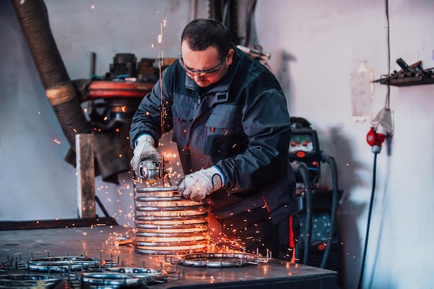 Locksmith in special clothes and goggles works in production Metal processing with angle grinder Sparks in metalworking