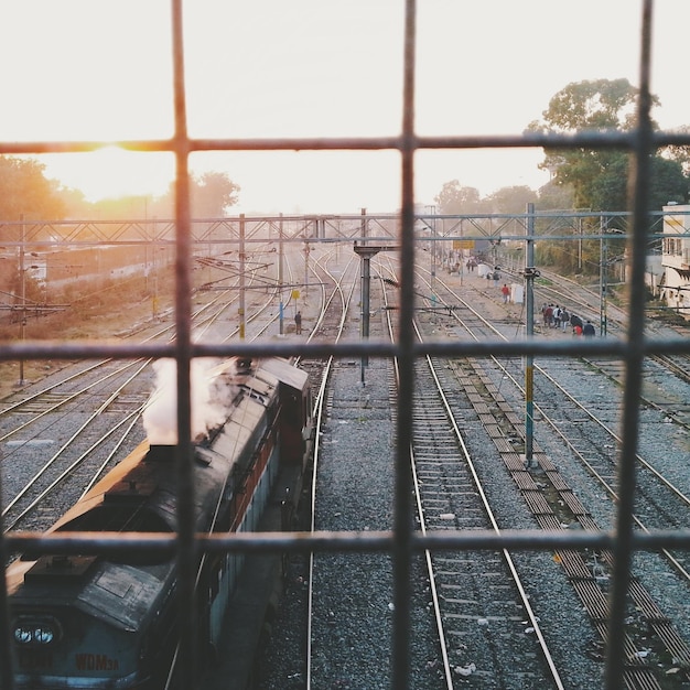 Foto locomotiva su binari ferroviari che vede attraverso la griglia