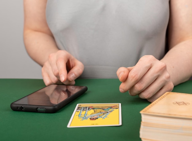 Lodz Poland March 31 2023 Tarot card reader with mobile phone smartphone telling reading online Modern fortune teller uses information technology