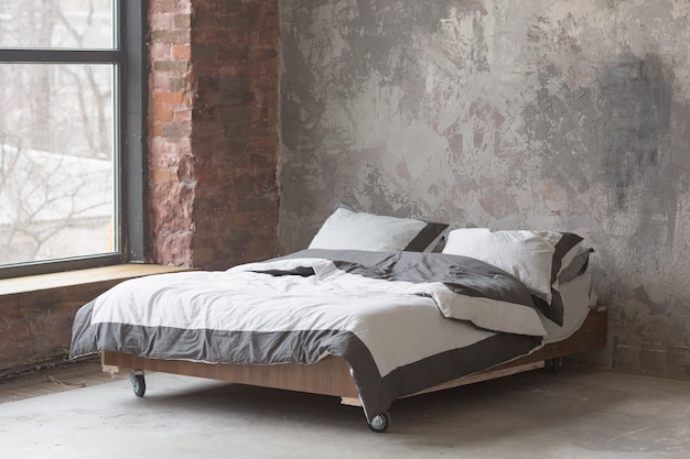 Loft-stijl slaapkamer interieur met groot bed, grijs design, baksteen textuur en betonnen wand