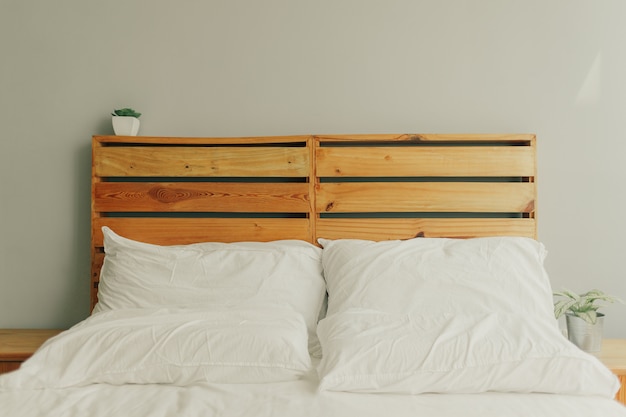 Loft wooden pine headboard with white bed.