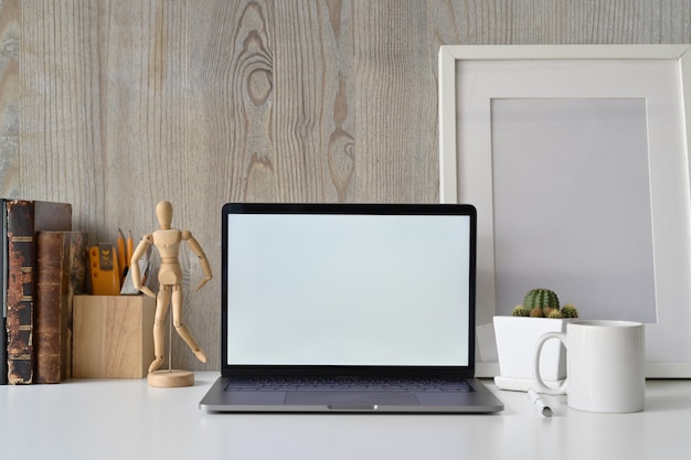 Loft workspace with blank white screen laptop and creative gadget.