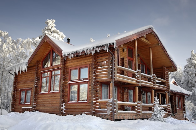 Log cabin with large windows, balcony and porch, modern house design, snowy winter.