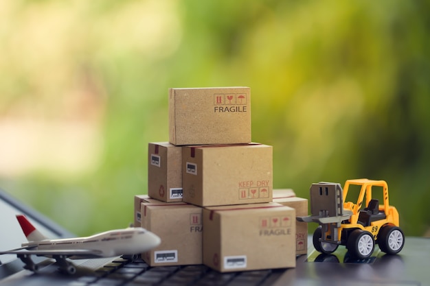 Photo logistic and cargo freight concept fork-lift a truck moves a paper box on notebook keyboard