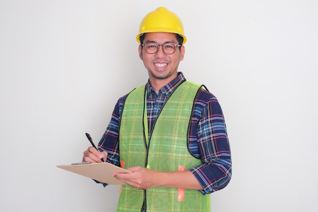 Photo a logistics staff smiling at the camera while fill in the checklist