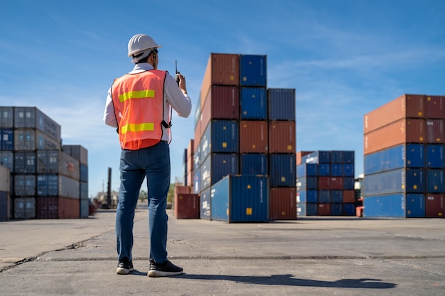 Logistiek engineer controle in de haven, containers laden voor vrachtwagens exporteren en logistiek importeren