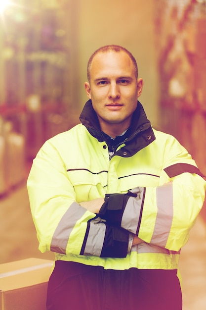 Foto logistiek, levering, verzending, mensen en exportconcept - gelukkige man of handwerker in overalls met dozen in het magazijn