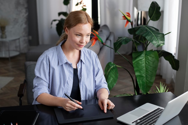 Photo logo designer working on her tablet connected to a laptop