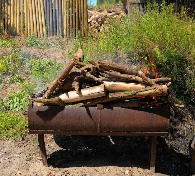 Photo logs are burning on an old iron grill summer sunny day in the countryside