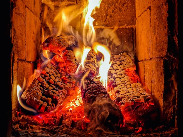 暖炉のストーブで燃える丸太が、木材と輝く石炭で燃えるキャンプファイヤーの炎をクローズアップ